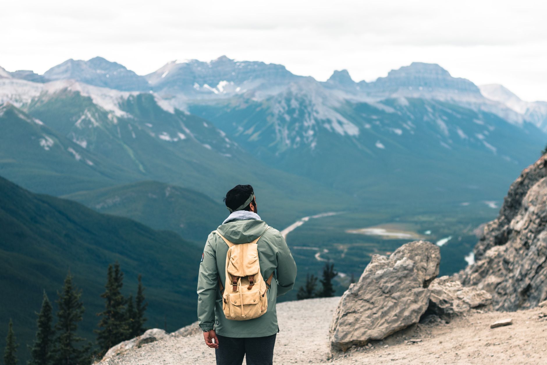 Hunter walking uphill on a rocky trail with a loaded daypack in preparation for a mountain stalk